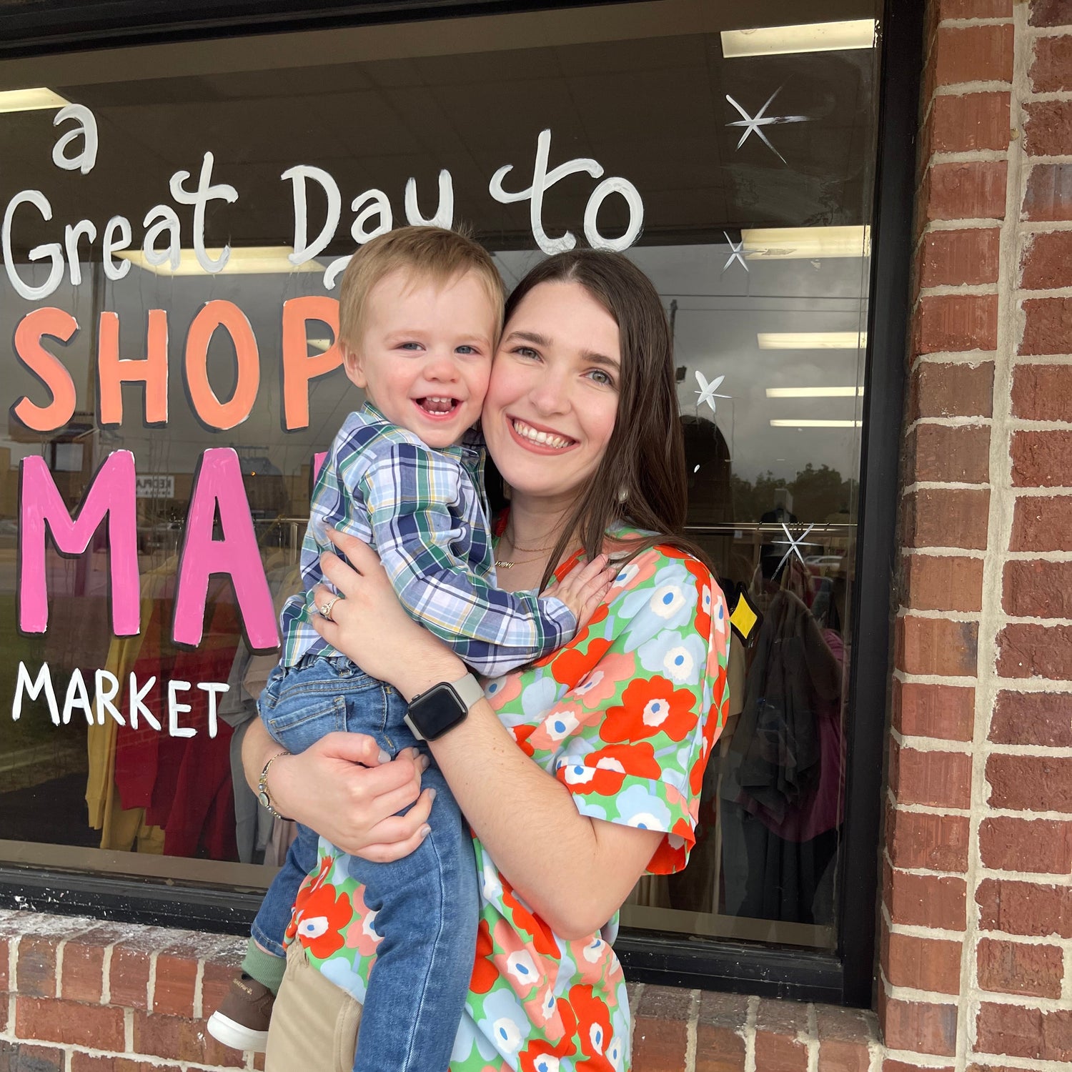 Woman and child standing in front of a store window with promotional text.